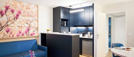 A modern kitchen with dark cabinets, a white countertop, and a built-in dishwasher.