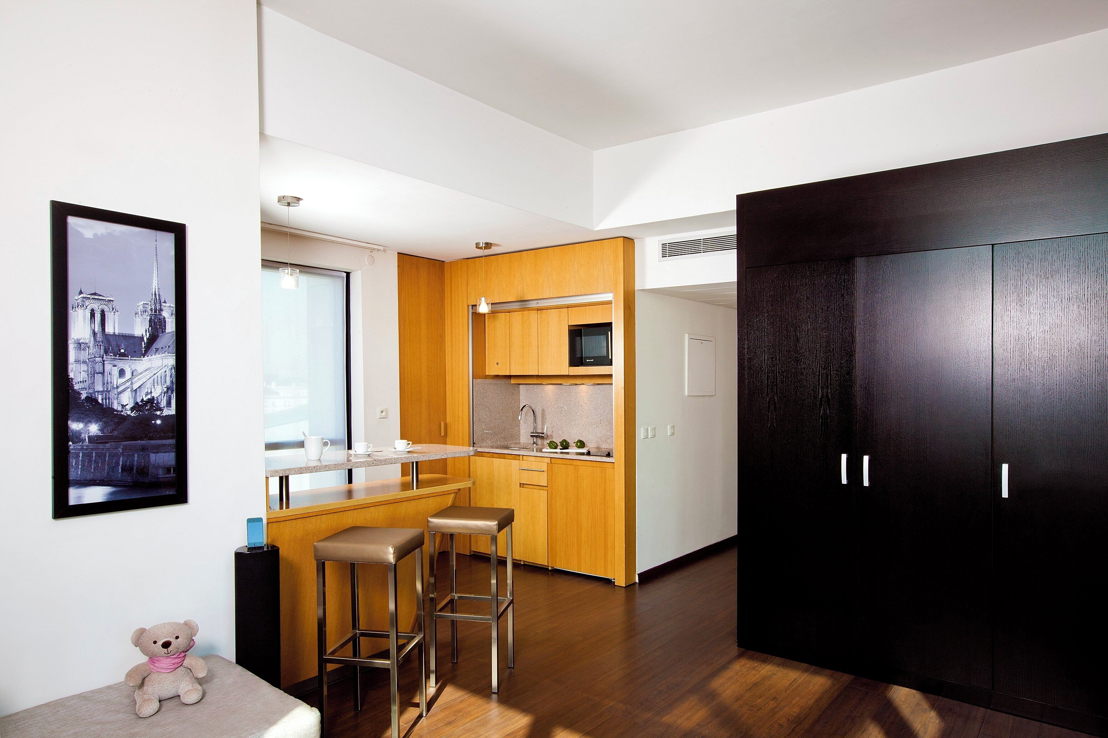 A modern kitchen with wooden cabinets, a stainless steel countertop, and a bar stool.