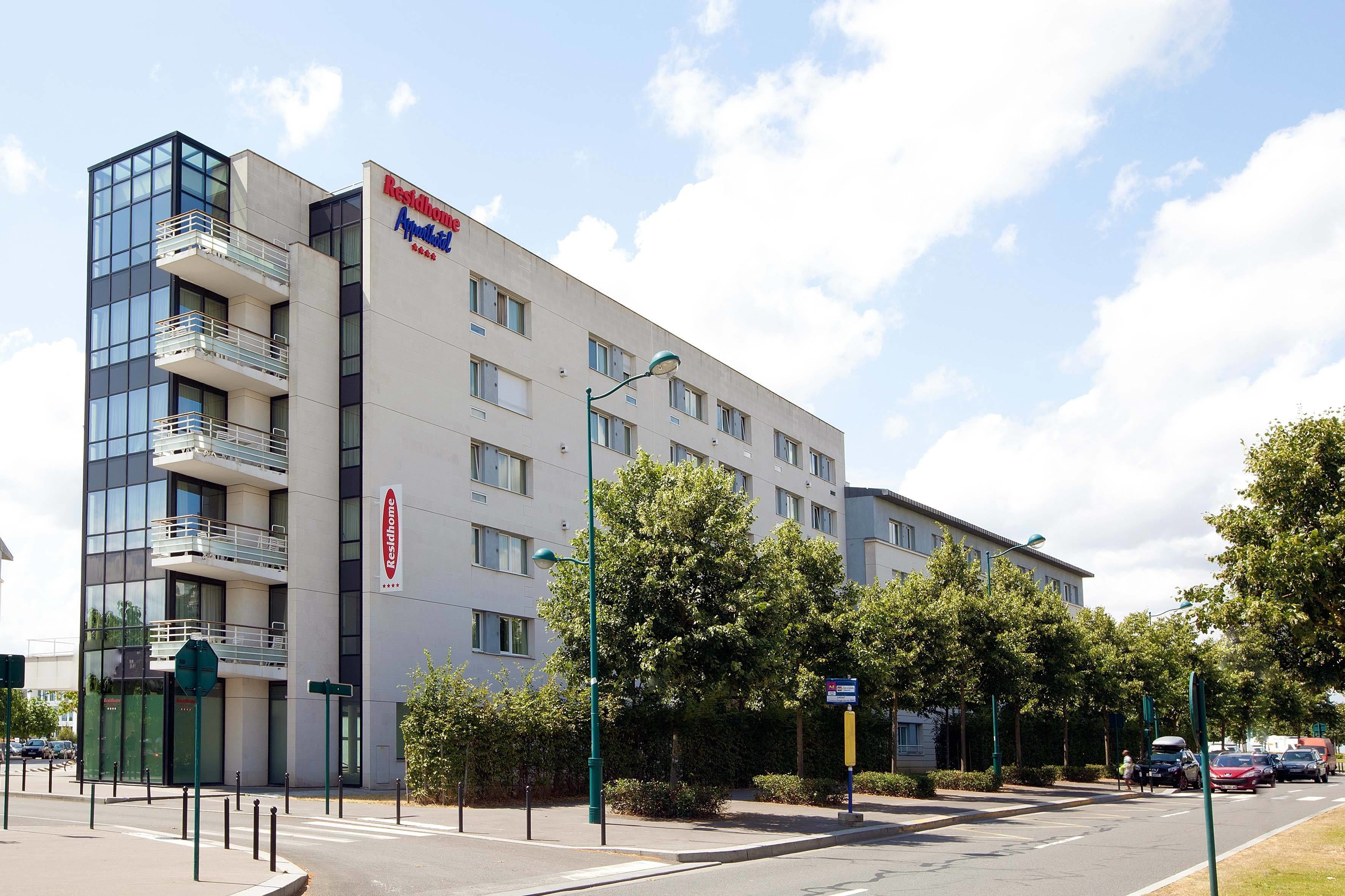 Un hôtel moderne doté d’une façade en verre, de nombreux balcons et d’une enseigne indiquant qu’il fait partie du réseau Relaishotels.