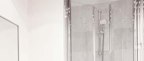 A modern bathroom with a glass-enclosed shower, a wooden vanity with a mirror, and a white towel.