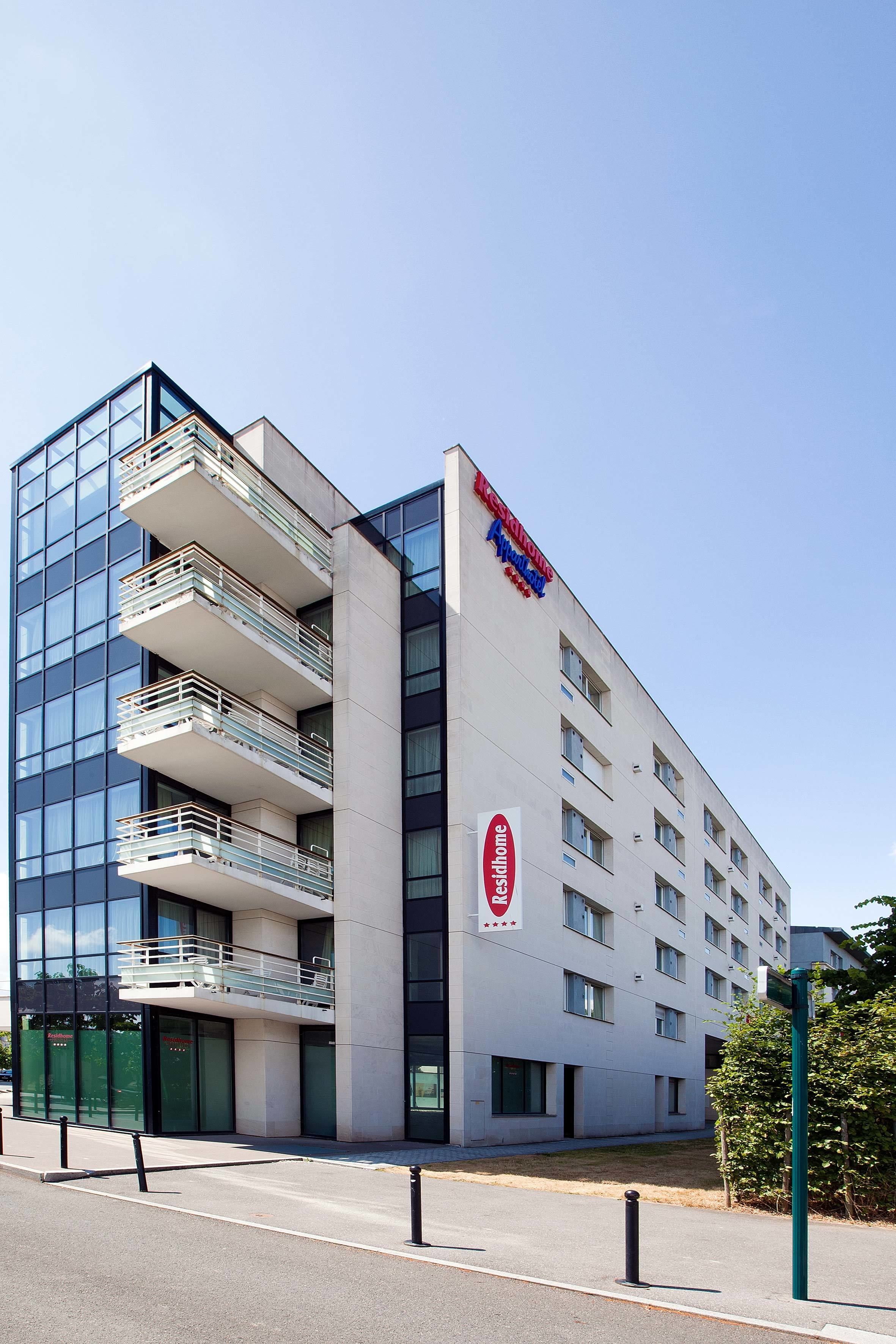 Un hôtel moderne doté d’une façade en verre, de nombreux balcons et d’une enseigne rouge et bleue bien visible.