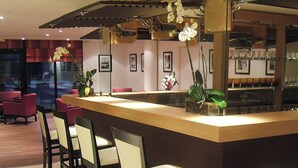 Un área de bar moderna con mostrador de madera, taburetes y orquídeas decorativas.