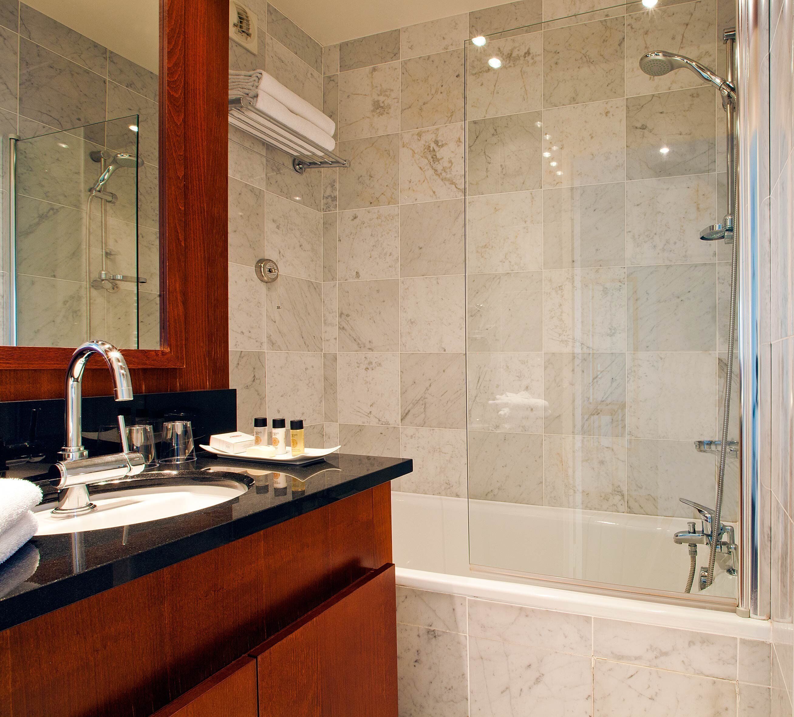 A modern bathroom with a glass-enclosed shower, a wooden vanity, and a large mirror.
