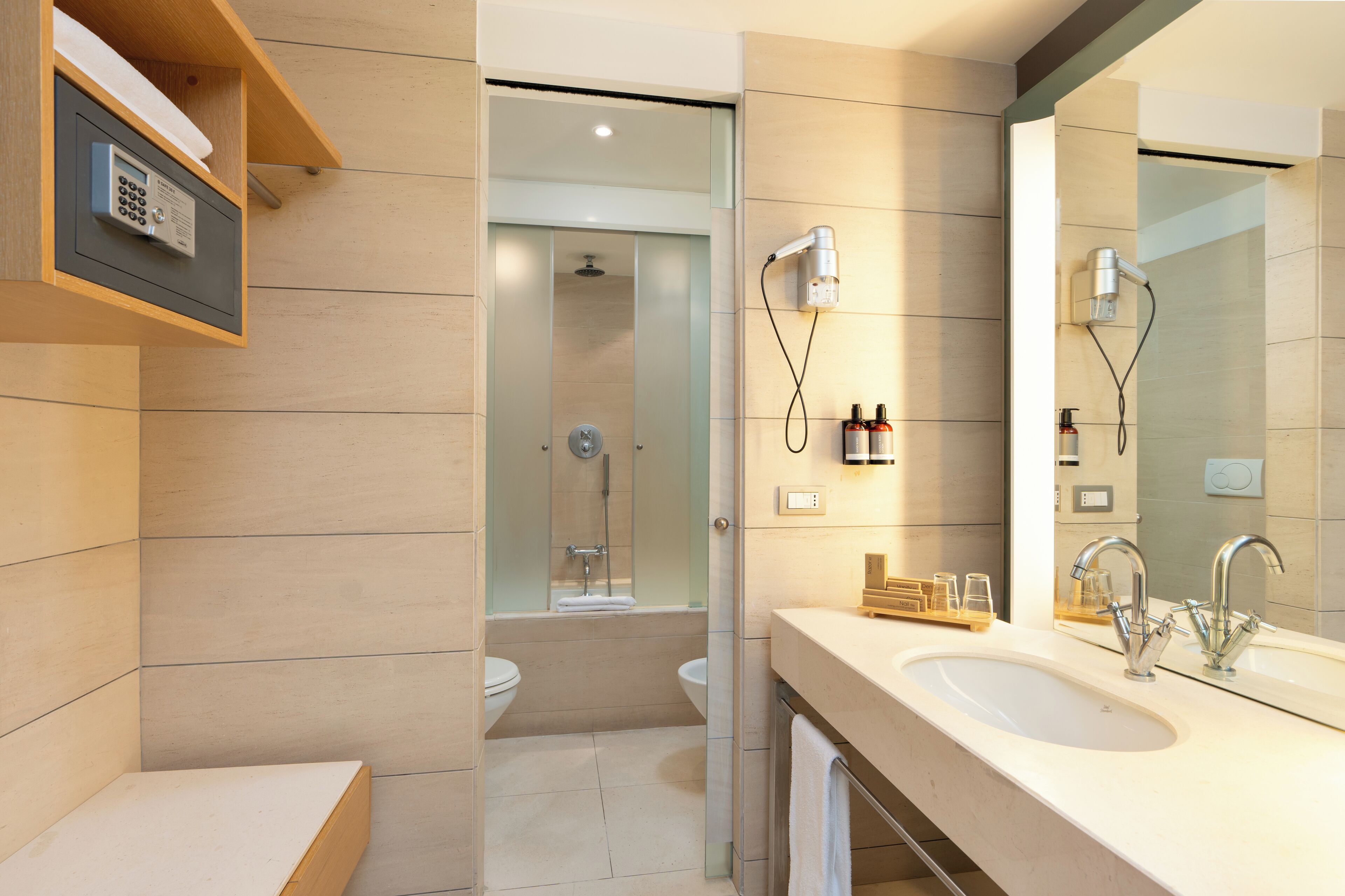 A modern bathroom with a large mirror, dual sinks, and a shower area.