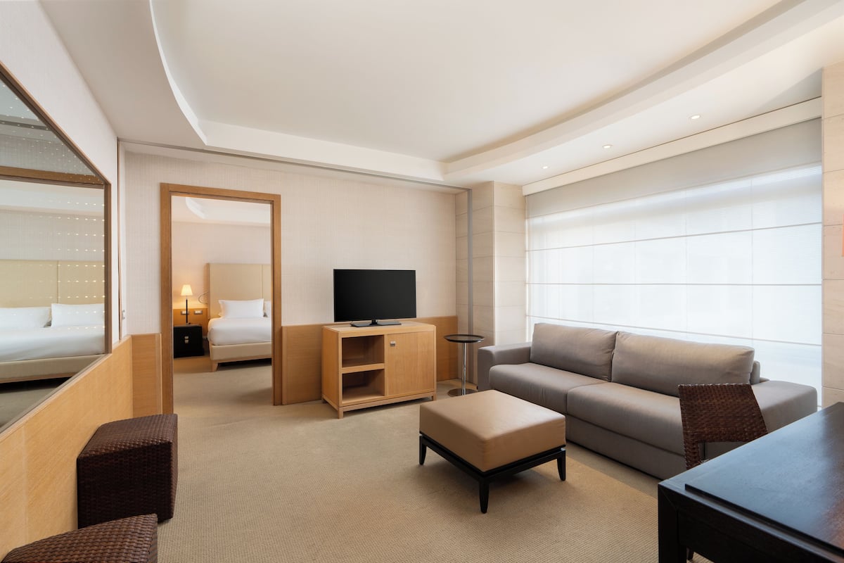 A modern hotel room with a large bed, a sofa, a TV, and a small table.
