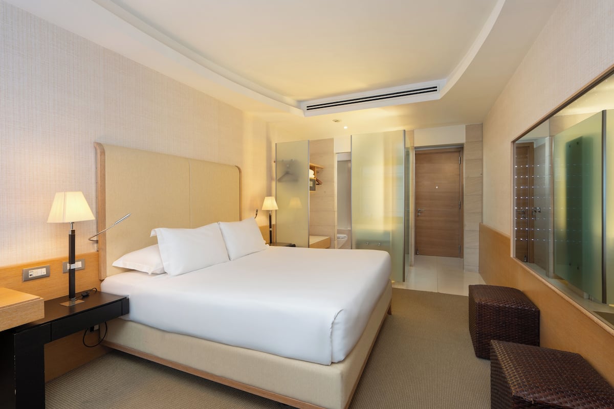 A hotel room with a large bed, bedside tables, a mirror, and a seating area.