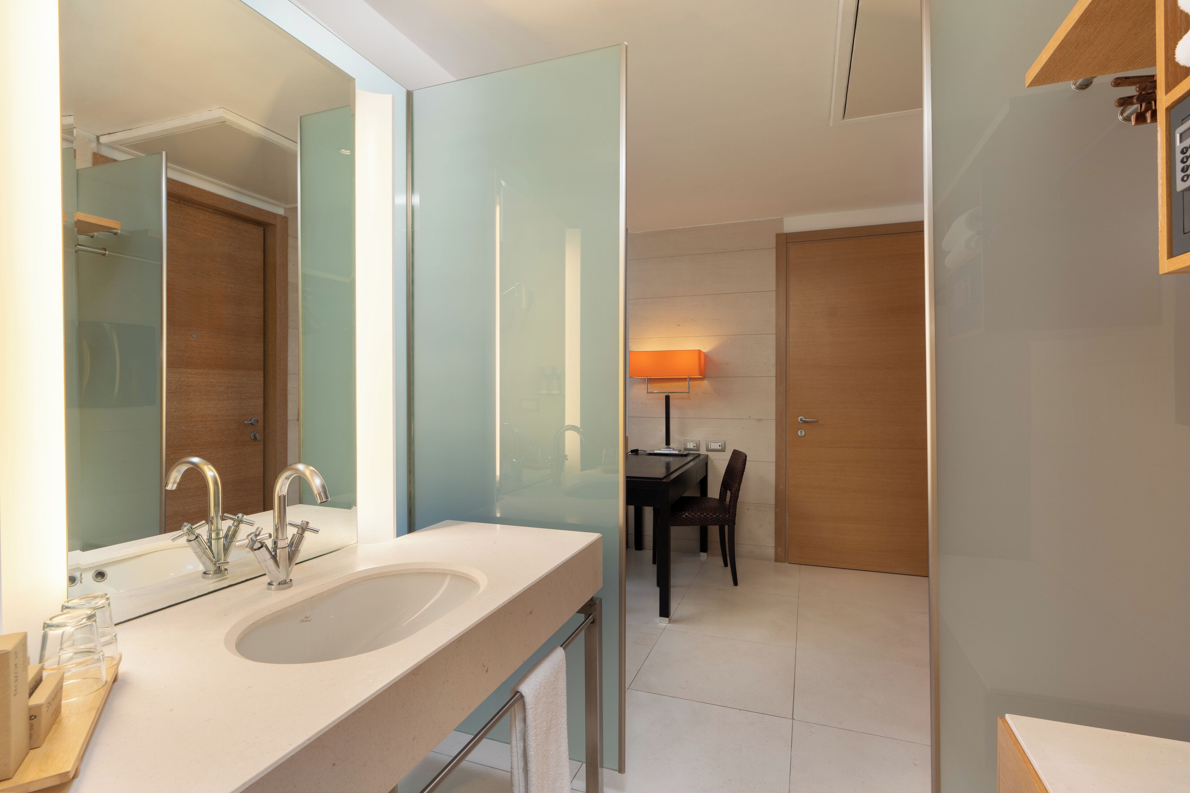A modern bathroom with a large mirror, two sinks, and a glass shower enclosure.