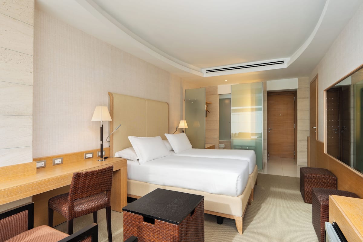 A hotel room with a bed, desk, chairs, and a bathroom visible through an open door.