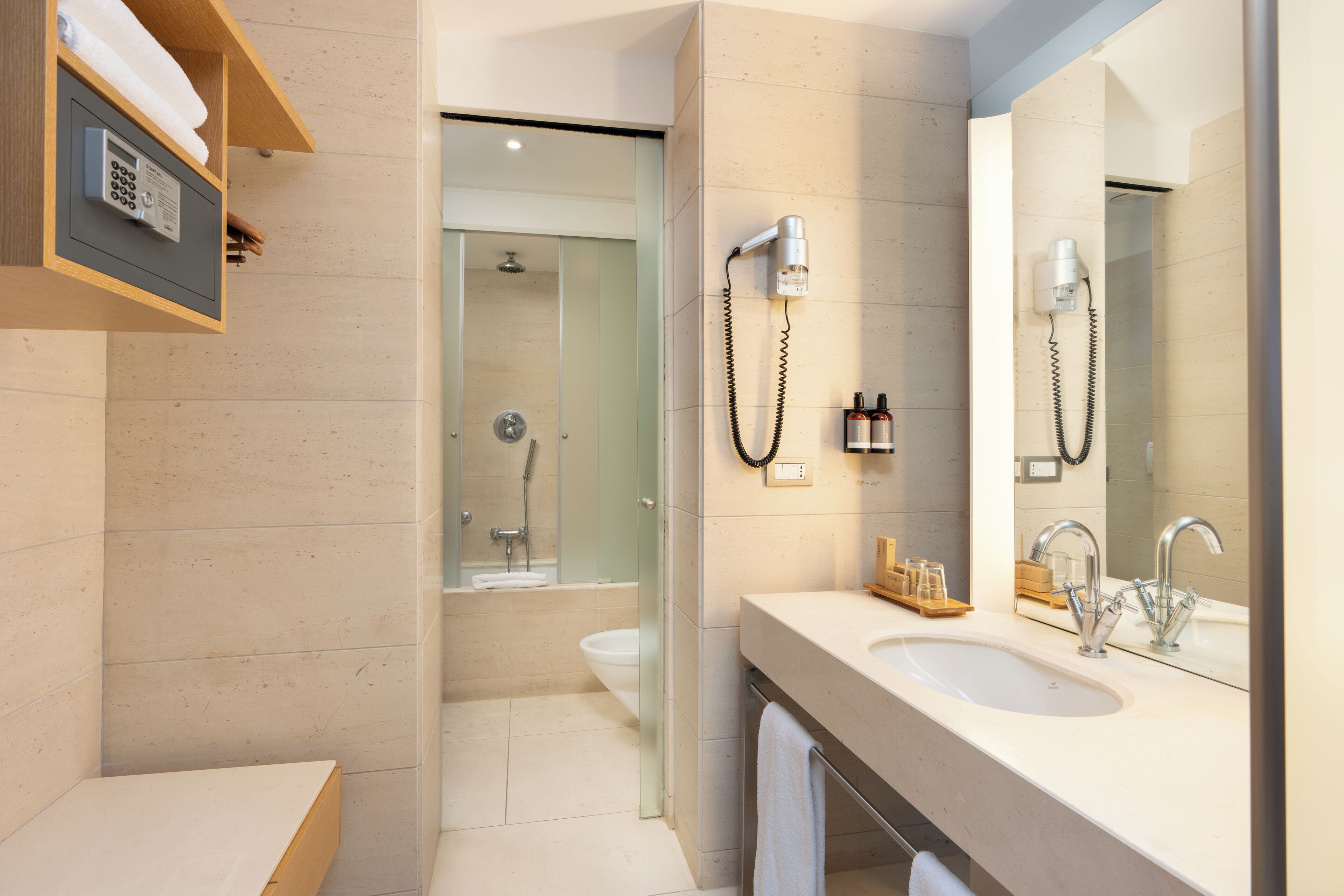 A modern bathroom with a large mirror, two sinks, a shower, and a towel rack.