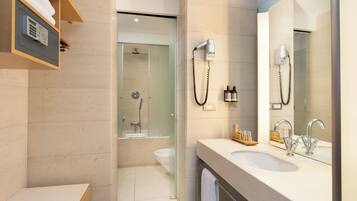 A modern bathroom with a large mirror, two sinks, a shower, and a towel rack.