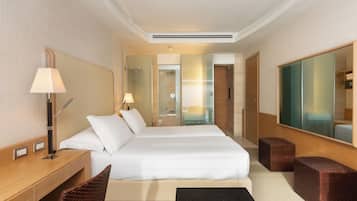Ein Hotelzimmer mit einem großen Bett, einem Schreibtisch mit Lampe, einem Spiegel und einer kleinen Sitzecke.