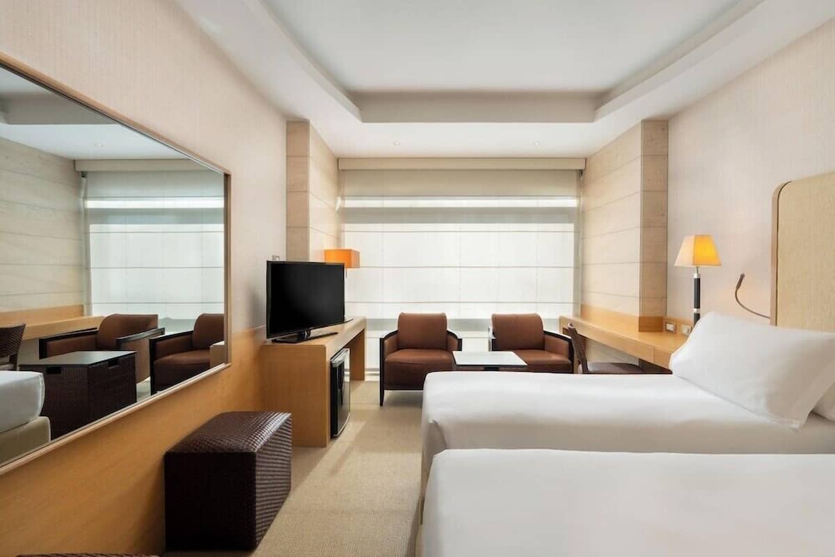 A hotel room with a bed, a TV, a desk, a chair, and a sofa.