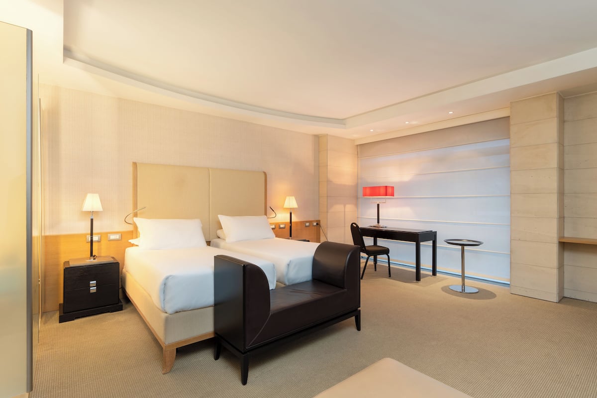 A hotel room with two beds, a sofa, a desk, and a chair.