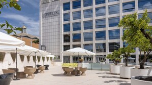 A hotel with outdoor seating and a modern building facade. - Precise House Mantegna Roma (Rome)