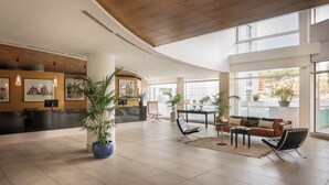 A spacious lobby with a high ceiling, large windows, and a reception desk. - Precise House Mantegna Roma (Rome)