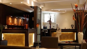 Eine moderne Hotelhalle mit Empfangstresen, Sitzgelegenheiten und Dekorationselementen.