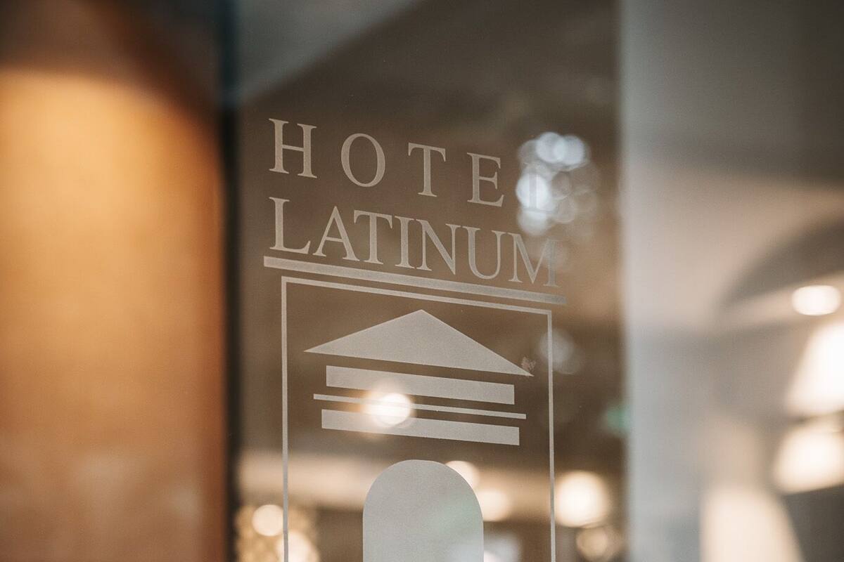 Se ve a través de un ventanal el letrero de un hotel con el nombre 'HOTEL LATINUM' y 'ROMA'.