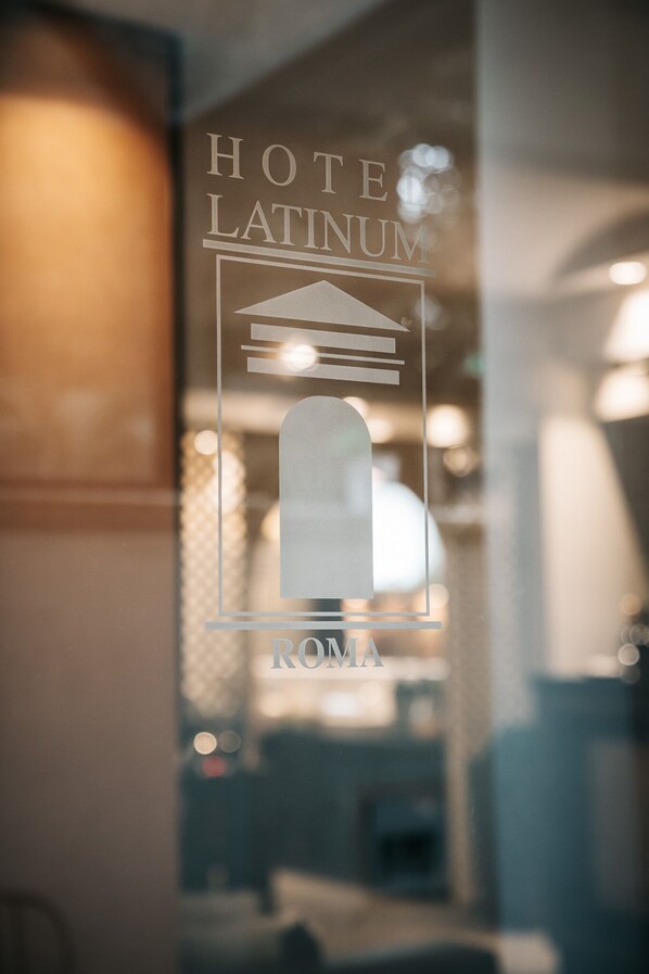 Se ve a través de un ventanal el letrero de un hotel con el nombre 'HOTEL LATINUM' y 'ROMA'.