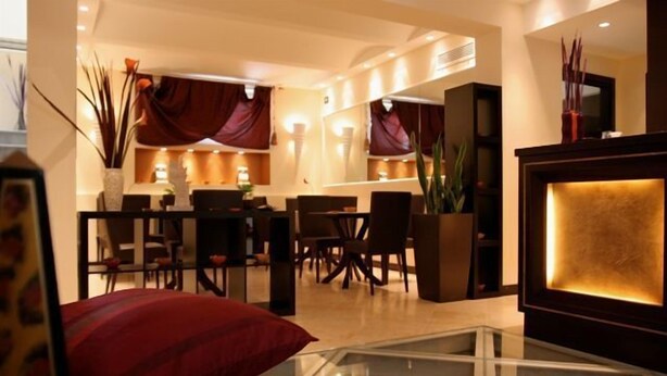 Eine moderne Hotellobby mit Essbereich, Rezeption und einem großen dekorativen Spiegel.