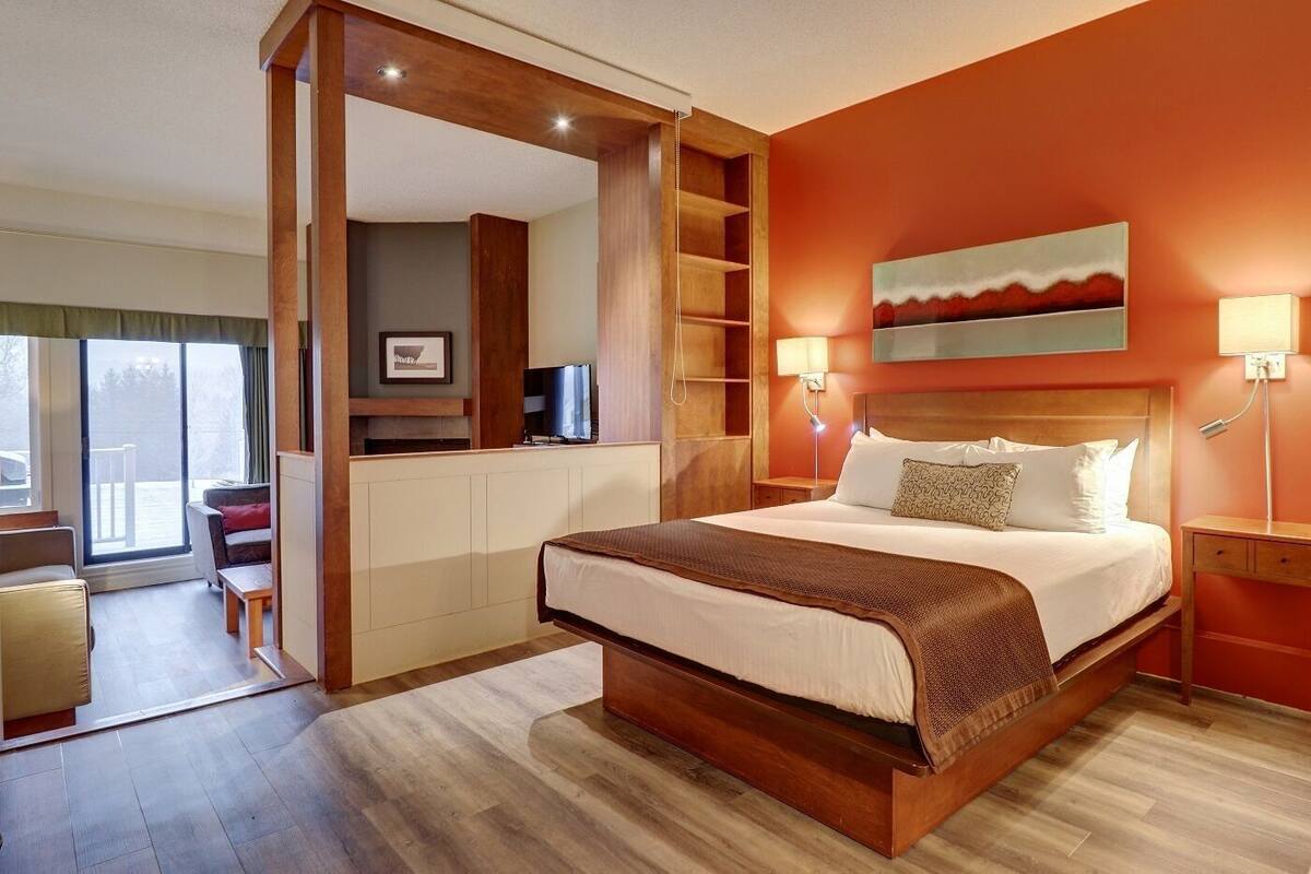 A hotel room with a large bed, a desk area, and a view of the outdoors.