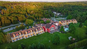 Un hotel grande con varias construcciones, piscina y césped bien cuidado.