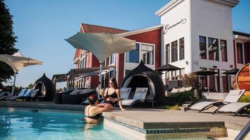 A pool area with lounge chairs, umbrellas, and a building with a sign that reads "Charming".