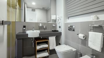 A modern bathroom with a large mirror, a sink, a toilet, and a shower area.