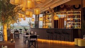 Un restaurant doté d’un plancher en bois, de lampes en osier suspendues et d’un bar avec des étagères remplies de bouteilles.