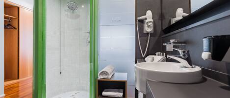 A modern bathroom with a green shower enclosure, a sink with a mirror, and a towel rack.
