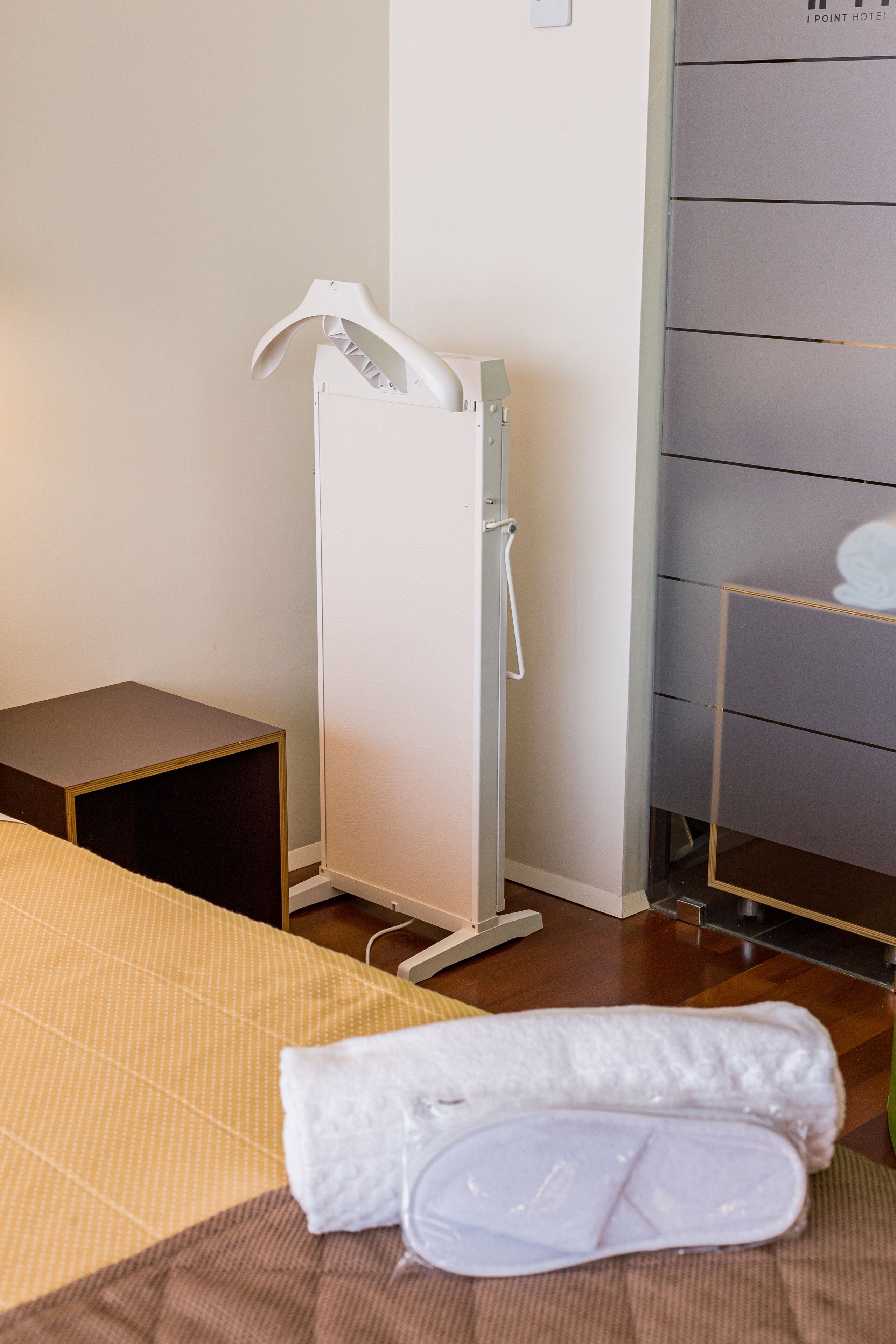 Ett hotellrum med en säng, ett sängbord, ett vitt element och en liten hylla med en dekorativ prydnad.