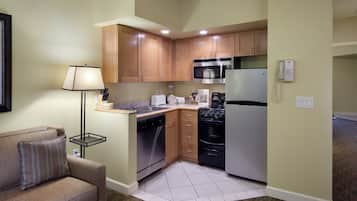 A compact kitchen with wooden cabinets, a microwave, a refrigerator, and a dishwasher.