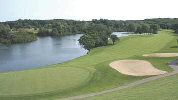 A golf course with a lake, sand bunkers, and a flag marking the hole.