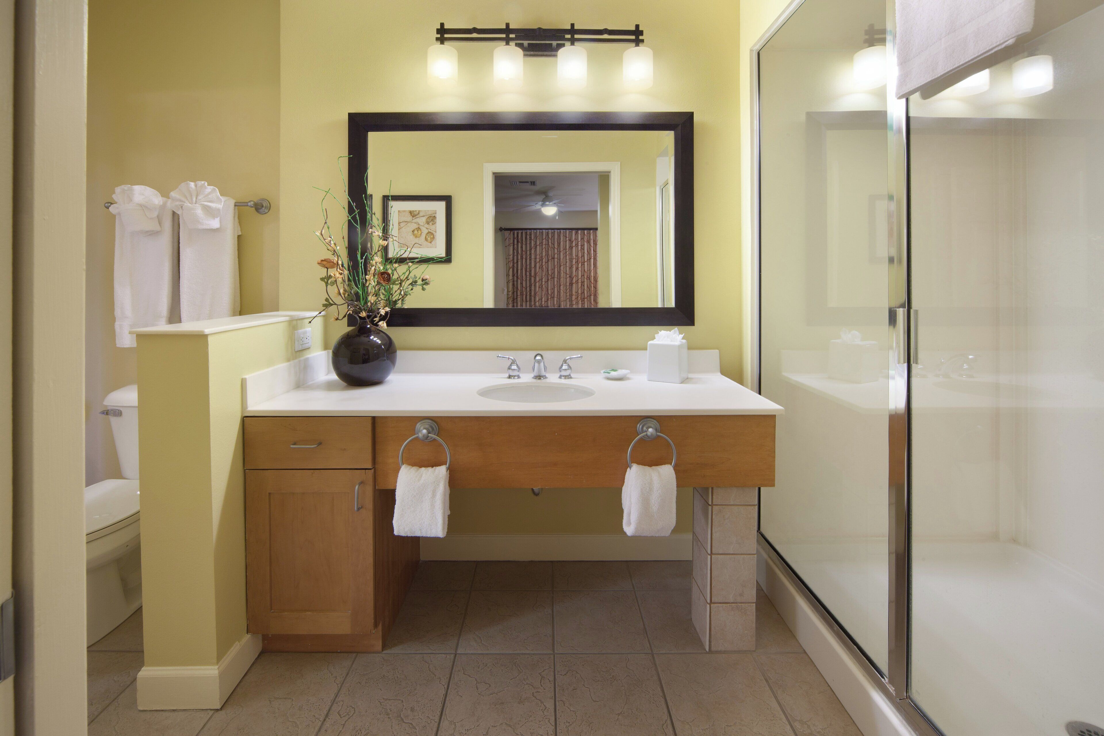 A bathroom with a white sink, a mirror, a toilet, and a shower.