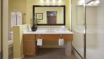 A bathroom with a white sink, a mirror, a toilet, and a shower.
