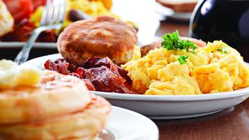 A breakfast plate with scrambled eggs, bacon, and toast.