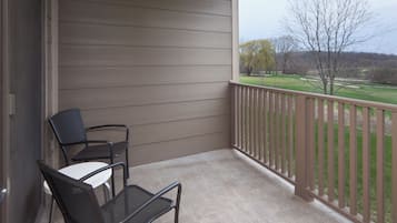 Ein Balkon mit Blick auf einen Golfplatz, ein Tisch und zwei Stühle.