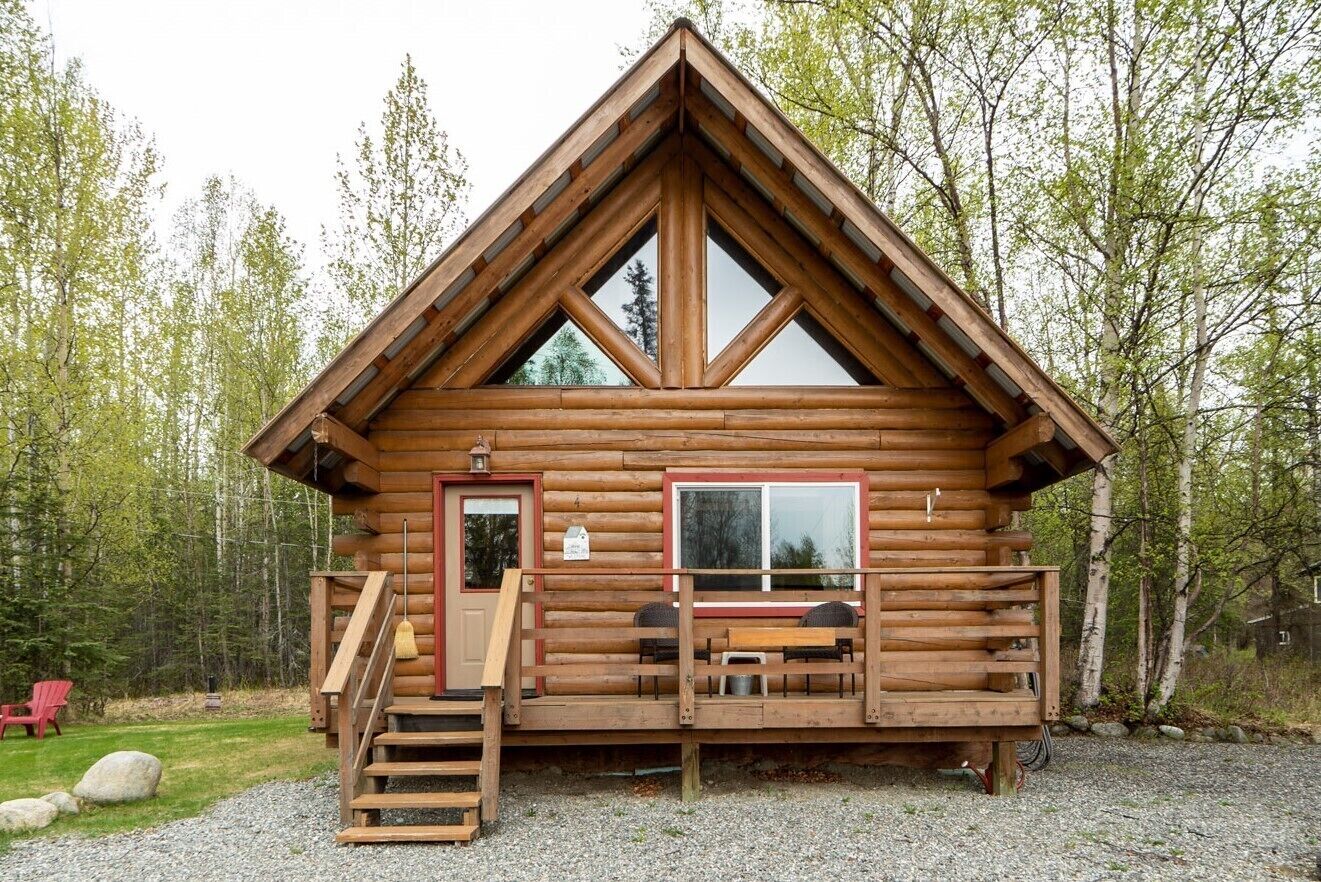 Een vakantiehuisje van hout met een houten terras, een voordeur en een raam.