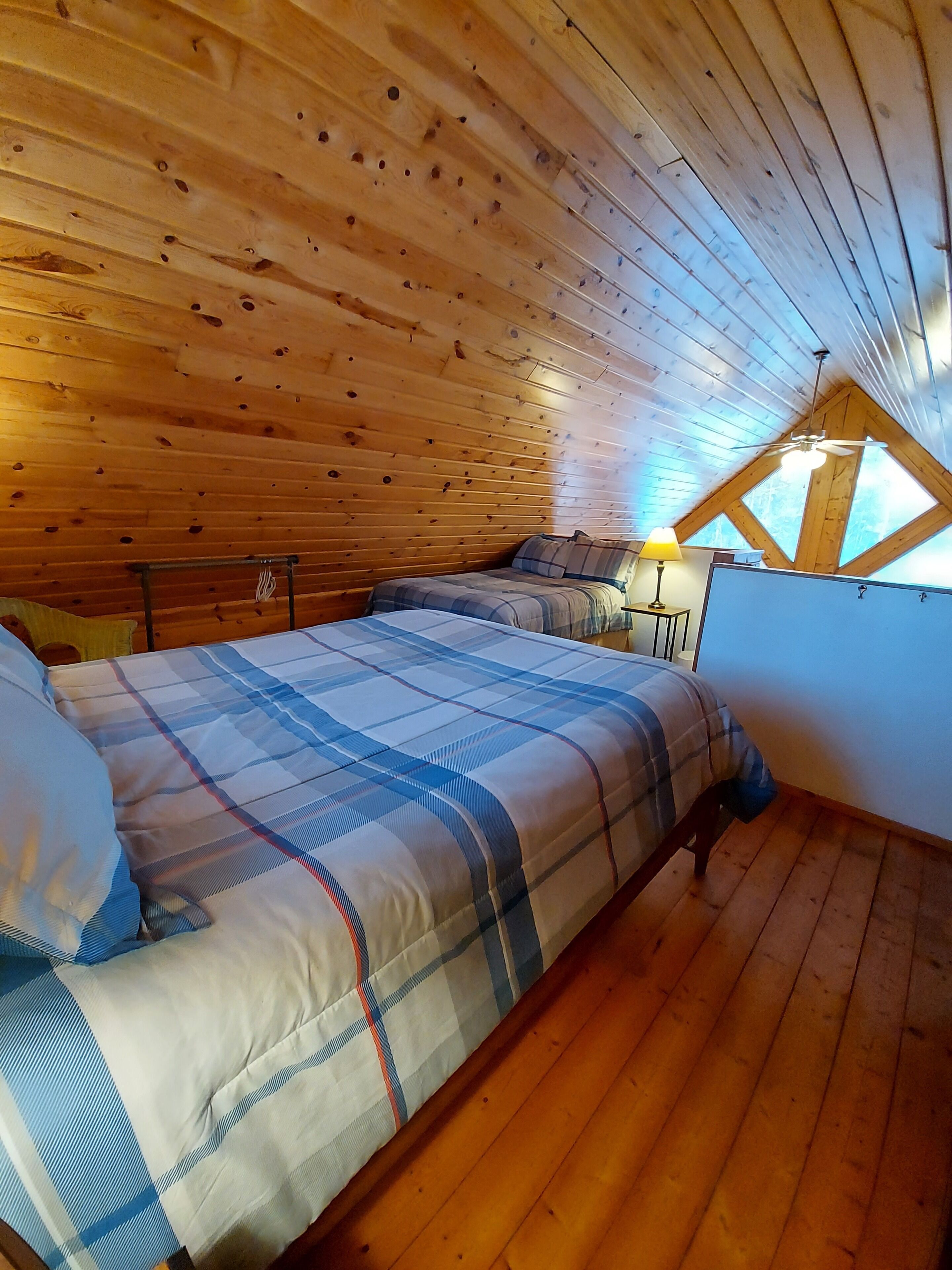 A cozy attic bedroom with wooden walls and a sloped ceiling.