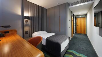 Een hotelkamer met een bed, een bureau, een stoel, een kast en een spiegel.