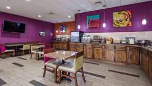 Een restaurant met een paars interieur, houten meubels en een keuken met inbouwapparatuur.