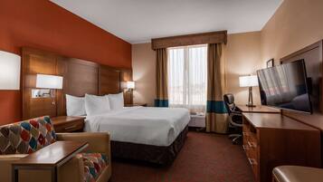 Une chambre d’hôtel avec un lit, un bureau, une télévision et une chaise.