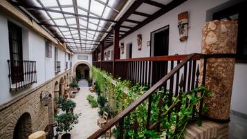 Un patio cubierto con una escalera central, plantas en macetas y una columna de piedra.