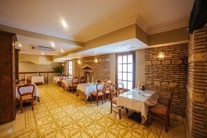 A dining area with multiple tables and chairs, a patterned floor, and a stone wall.