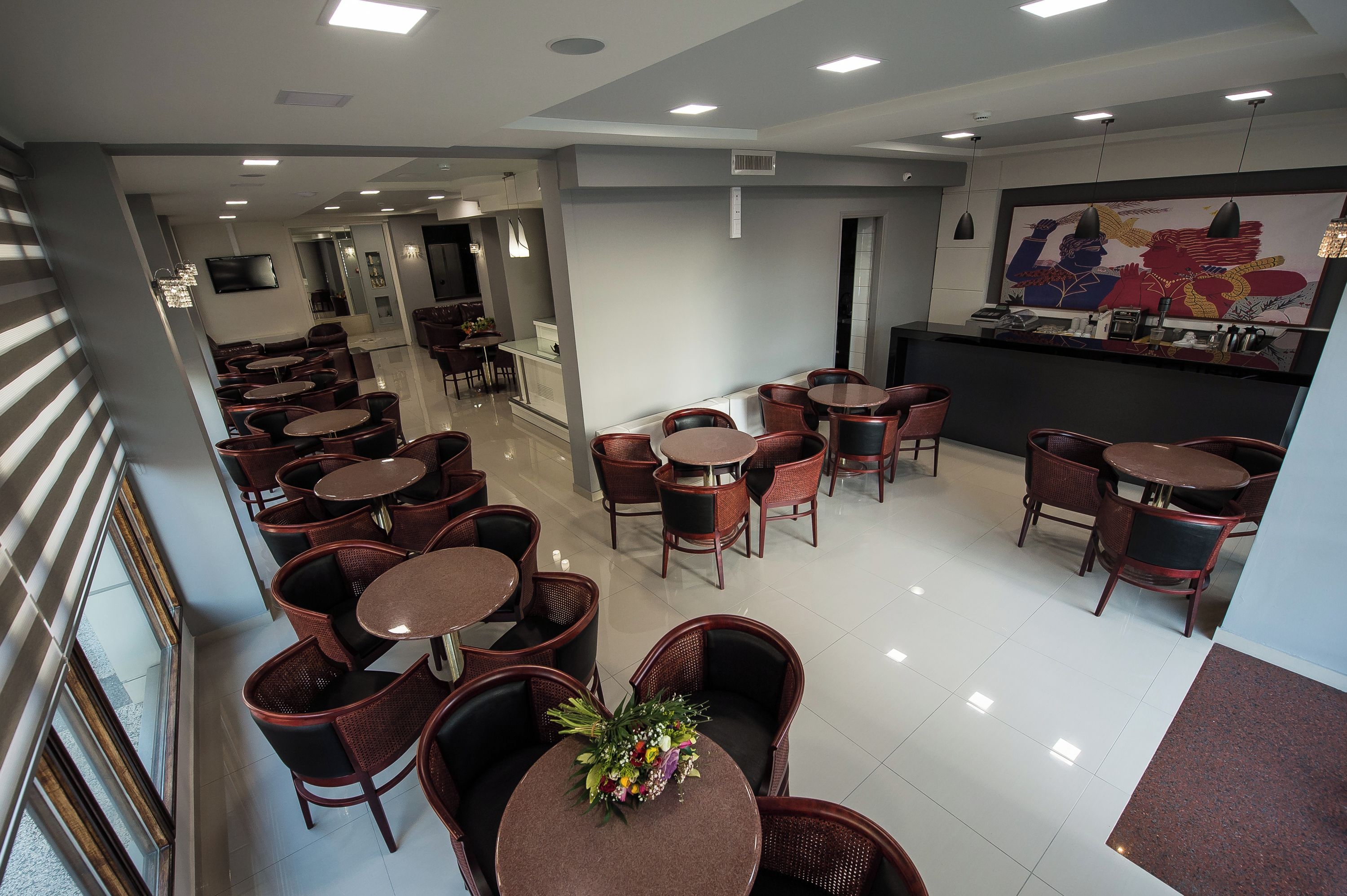 A hotel lobby with multiple seating areas, a reception desk, and a large wall mural.