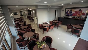A hotel lobby with multiple seating areas, a reception desk, and a large wall mural.