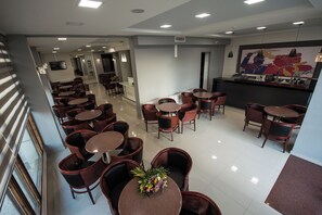 Un vestíbulo de hotel con varias zonas de estar, una recepción y un mural grande en la pared.