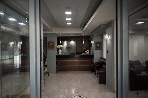 Un'area reception con scrivania, un lampadario e un angolo salotto con divano e poltrone.