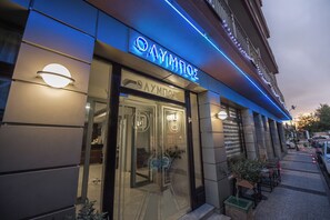 Un edificio con facciata in vetro, insegna al neon e ingresso ben visibile.