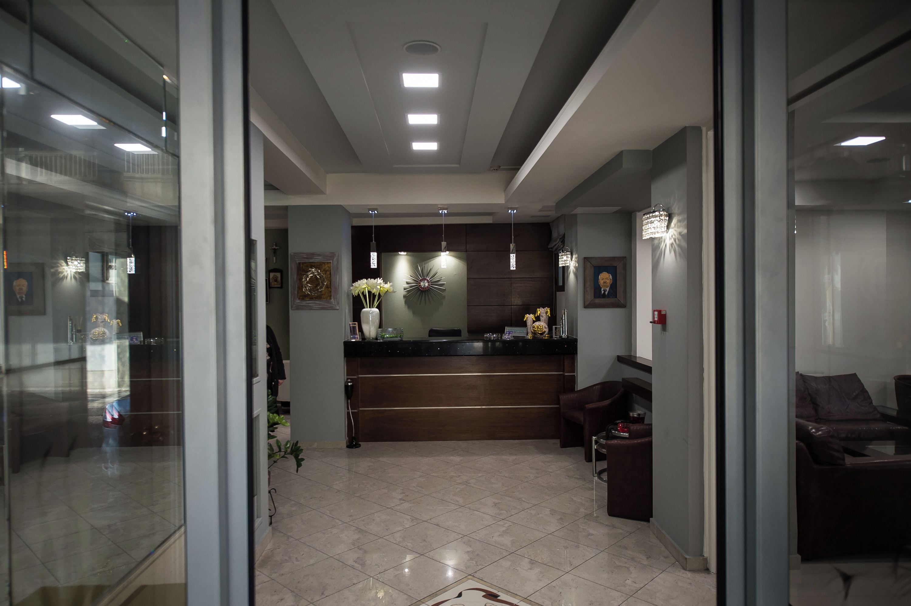 A reception area with a reception desk, a chandelier, and a seating area with a couch and chairs.