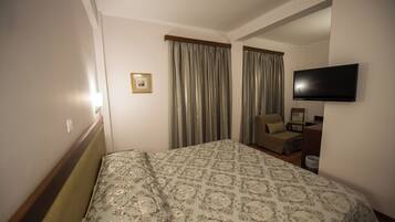 Ein Hotelzimmer mit einem Bett, einem Sessel, einem Fernseher und einem Bild an der Wand.